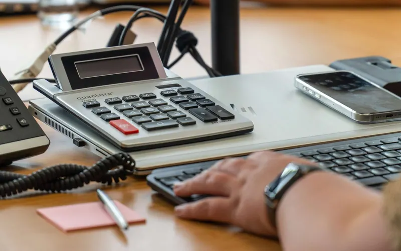 Rekenmachine, telefoon en toetsenbord op een bureau bij IZI!