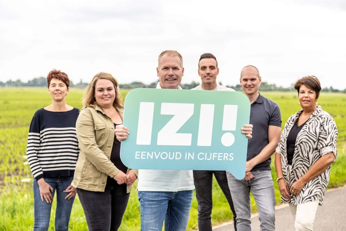 Het team van IZI! in de polder, met het bord ‘IZI! Eenvoud in cijfers’